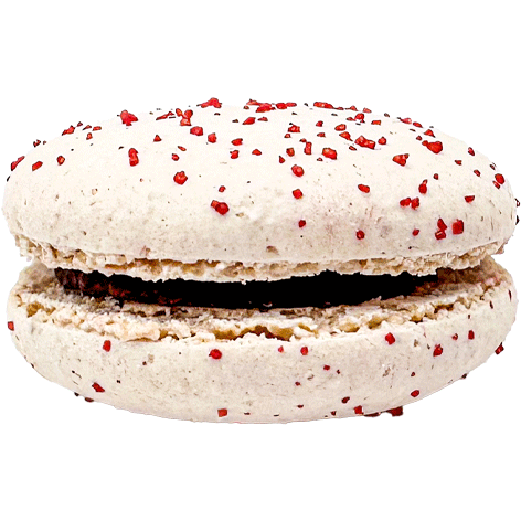 Light coloured macaron with red sprinkles, and a dark chocolatey filling